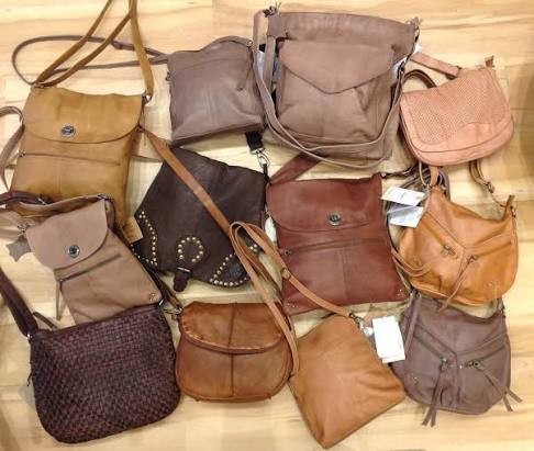 Collection of relic handbags including a crossbody, tote and satchel arranged on a wooden table